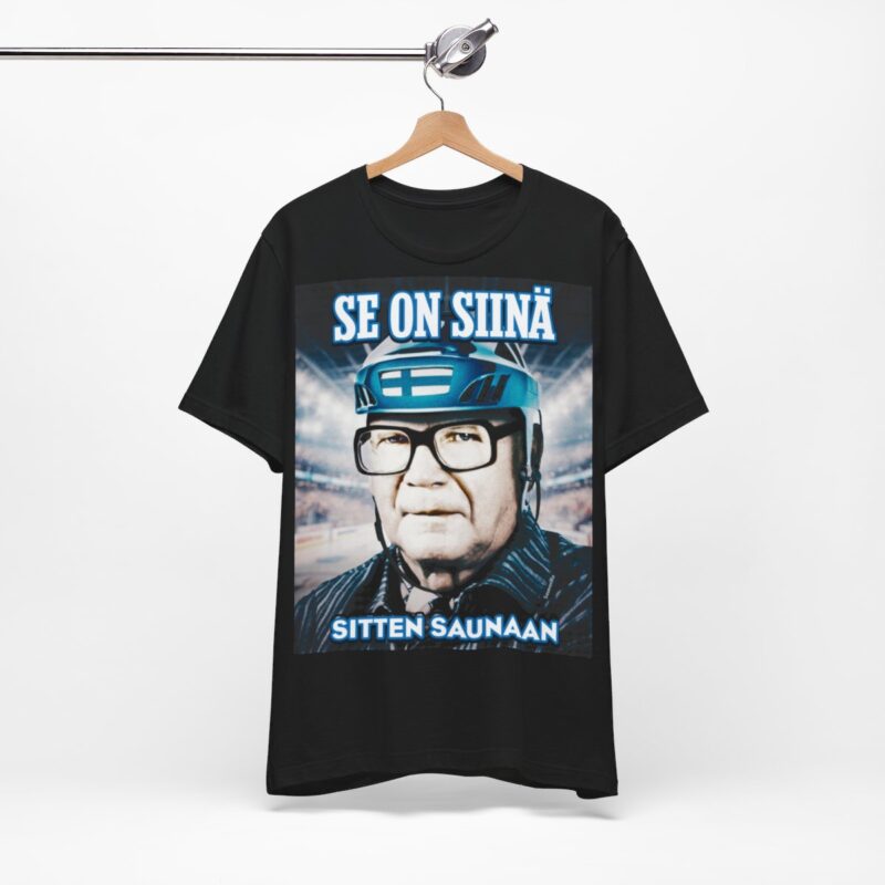 Musta Kekkonen T-paita roikkumassa telineessä. Musta Jääkiekko T-paita joka on samalla myös musta Kekkonen T-paita, eli kaksi suomalaista klassikkoa yhdessä suositussa tuotteessa. Musta Kekkonen paita sopii jääkiekkoareenalle sekä kotikatsomoihin. Se on siinä ja sitten saunaan, sanoo Kekkonen paita ja musta miesten T-paita.