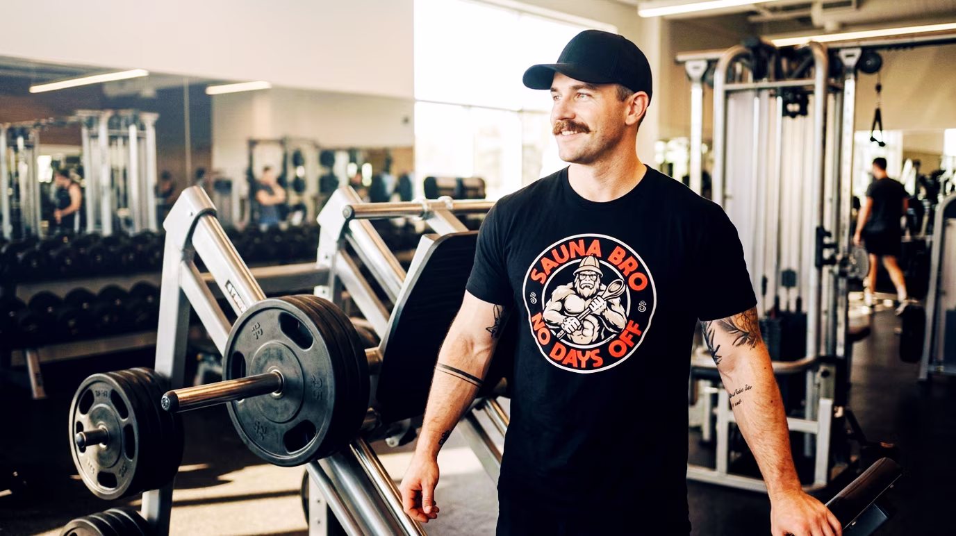 Sauna Bro T-shirt - No Days Off. In the image is our gym bro wearing the popular Sauna Bro tee, resting between sets and getting ready for the daily sauna session.